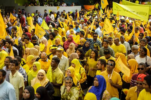Free A large gathering of people in yellow attire carrying flags during a daylight outdoor rally. Stock Photo