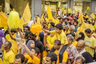 身穿黄色衣服的人群在热闹的街头举着旗帜，欢呼雀跃地抗议