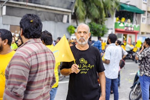 Man Standing and Holding Yellow Mini Flag