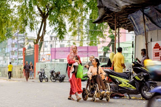 Two women, one in a wheelchair, navigate a lively urban street, capturing daily life and accessibility.