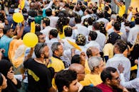 街头集会充满活力，手持黄色五彩纸屑和气球的人群多元而活跃