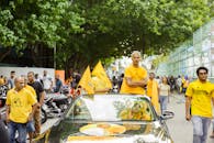 城市集会以身穿鲜艳黄色服装的人群和汽车为特色，展现了街头集会的活力