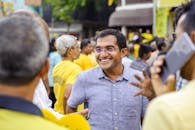 一个开朗的男人身处户外聚会，周围都是穿着黄色衣服的人