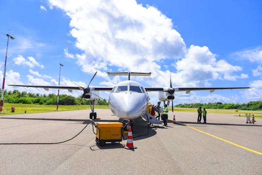 Front view of a propeller aircraft on a sunny runway with crew, surrounded by vibrant greenery in Maldives.