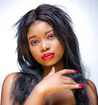Close-up portrait of a woman with vibrant makeup and expressive pose, showcasing beauty and elegance.