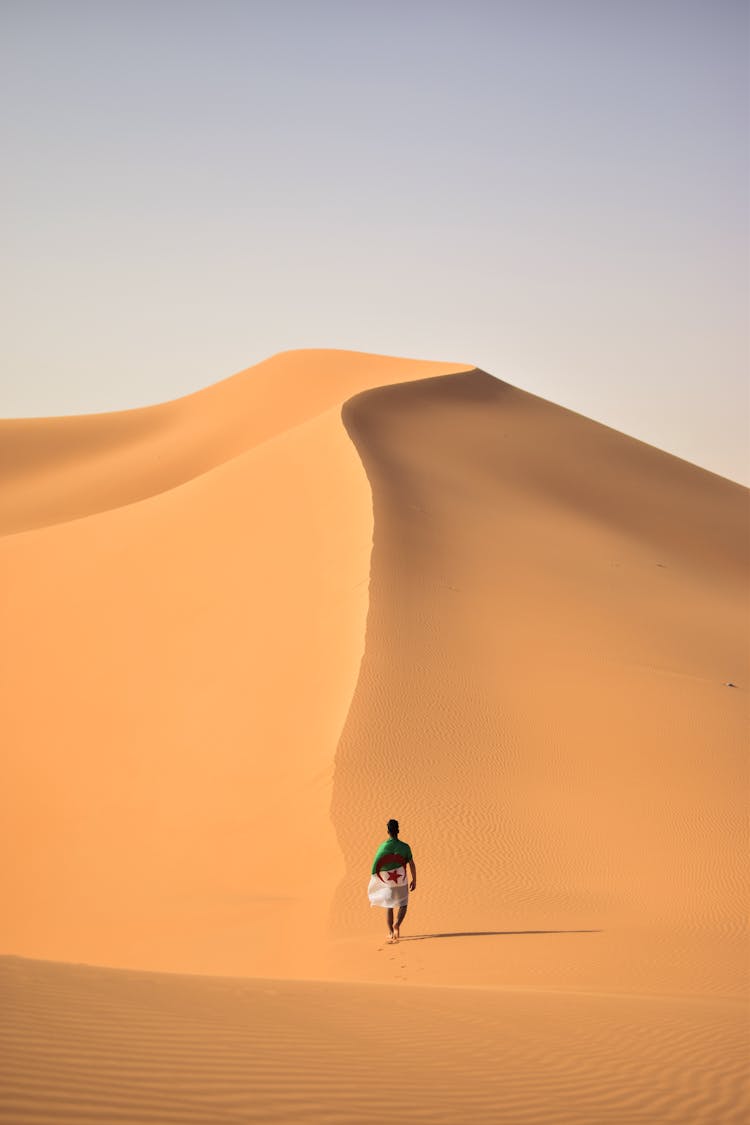 A Person Walking In The Middle Of The Hot Desert