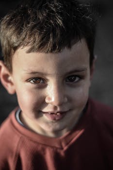 一个孩子在户外自然光线下拍摄的肖像，脸上挂着灿烂的微笑，显得很快乐