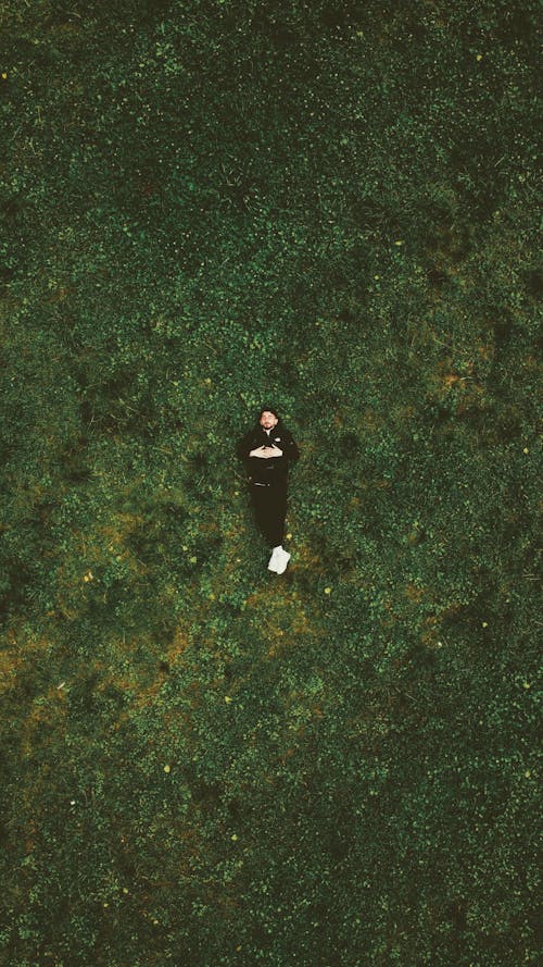 A person laying on the grass in the middle of a field