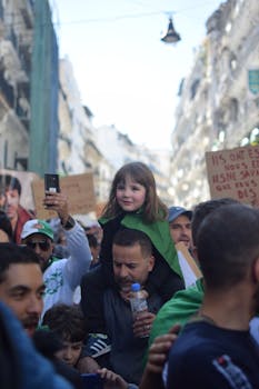在阿尔及利亚一场充满活力的街头集会上，一位父亲将女儿扛在肩上