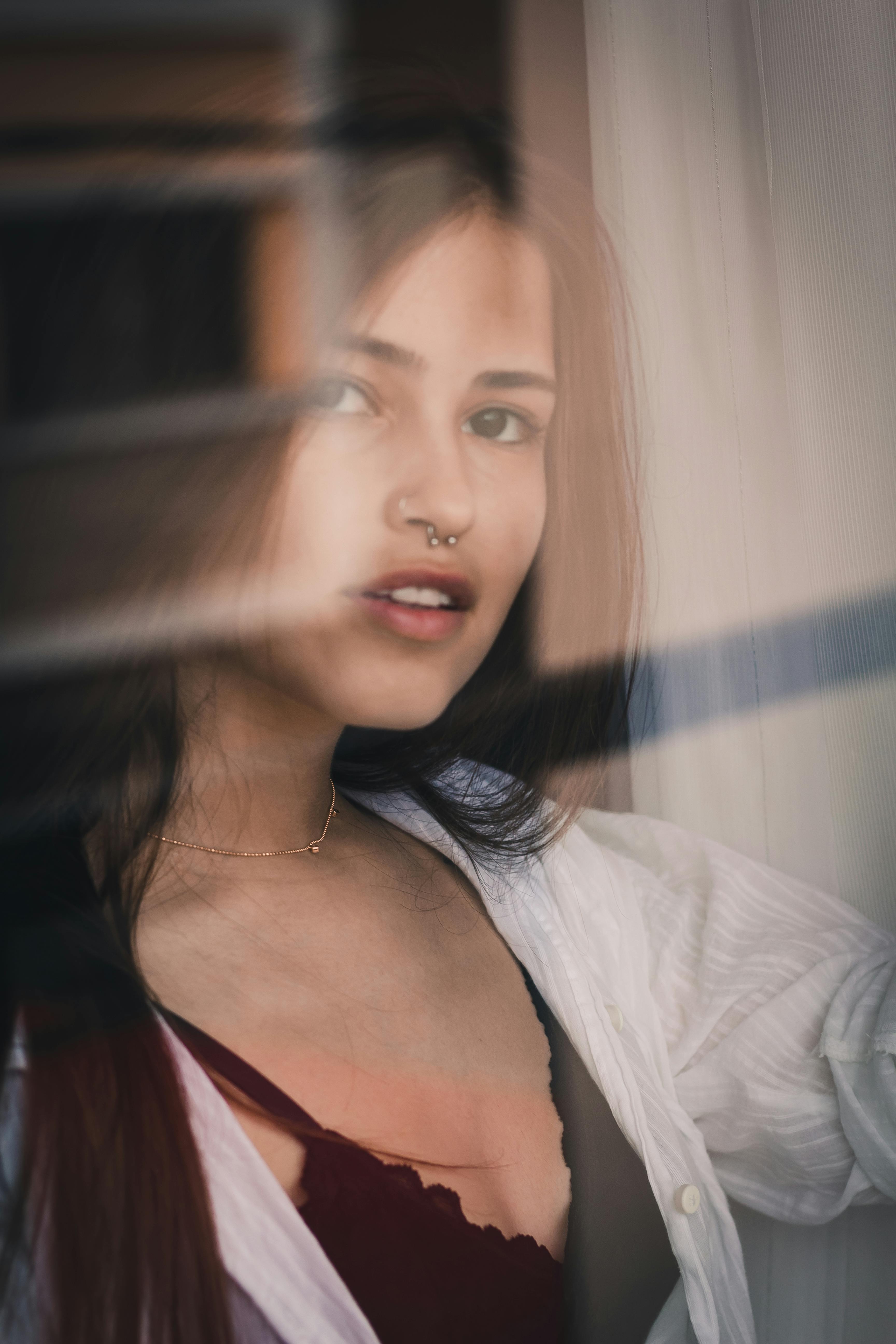 一位美丽的女子鼻穿环饰，凭窗凝望，尽显闲适优雅