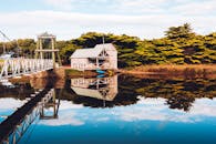 澳大利亚墨尔本的平静湖面上，倒映着船库和桥梁的风景