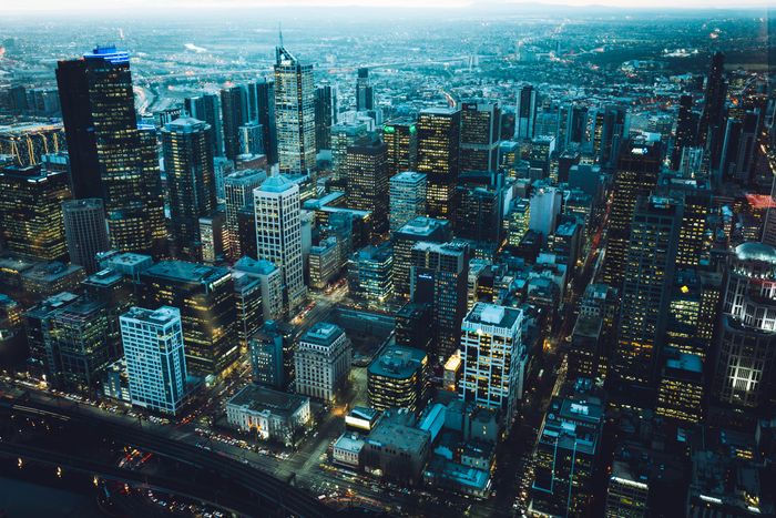 Aerial view of a dense city skyline at dusk, some towers lit and others dark