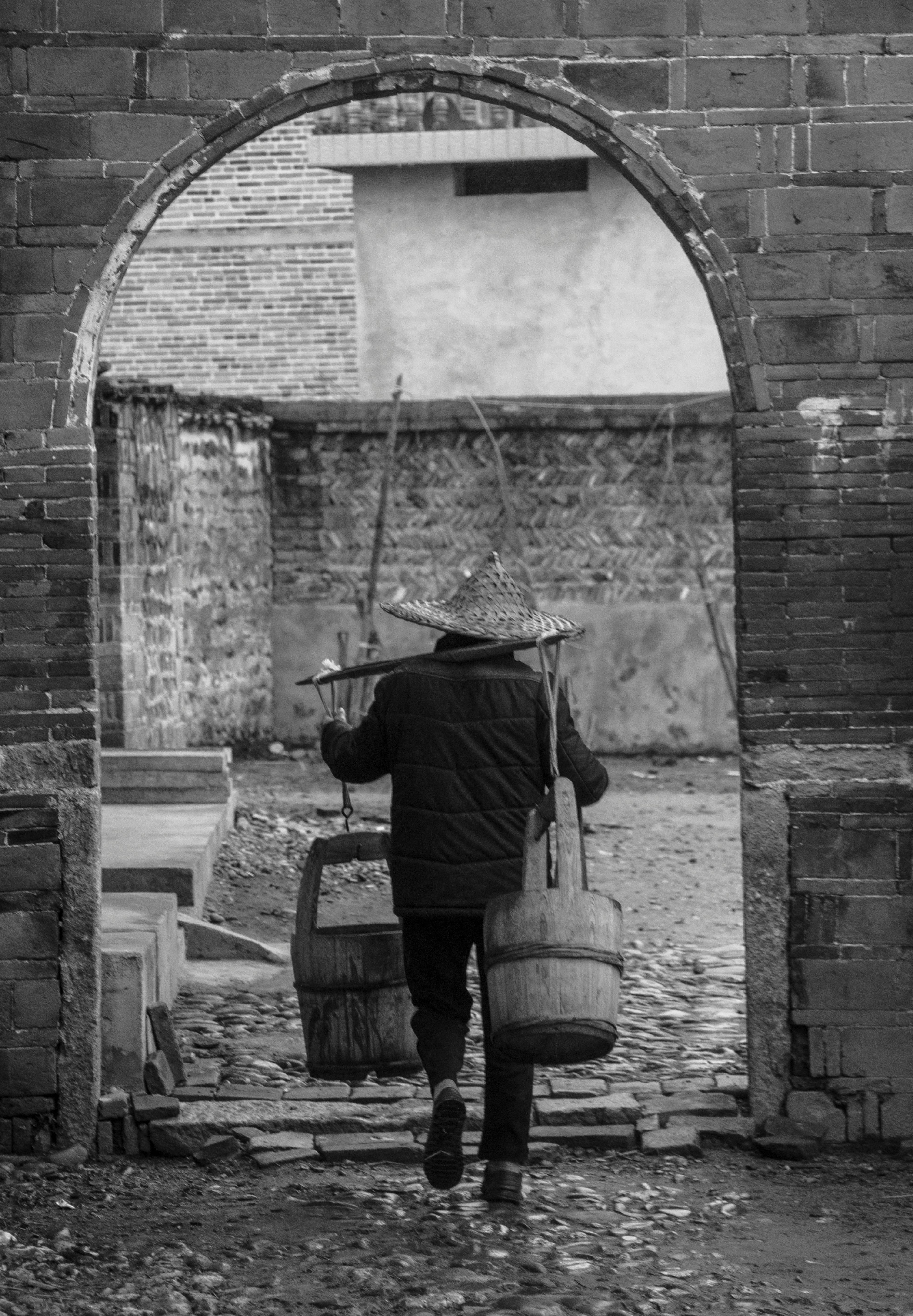 man carrying barrel in black and white photography