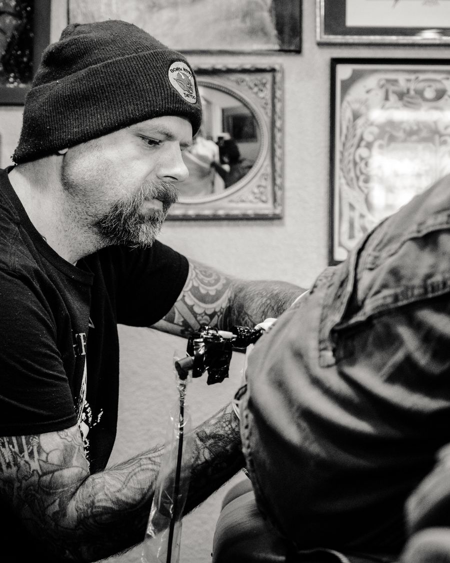 A tattoo artist at work on a client's back.