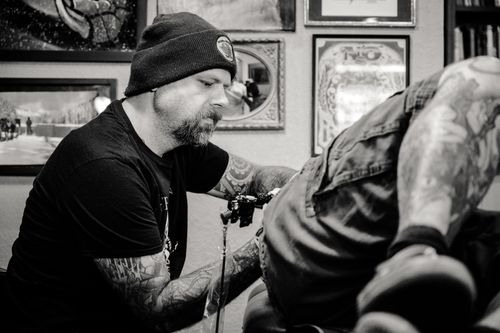 Free Tattoo artist focused on creating a design in a studio setting. Stock Photo