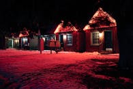 冬季夜晚，舒适的砖砌房屋外墙闪烁着红色霓虹灯，为雪地景观增添了光彩