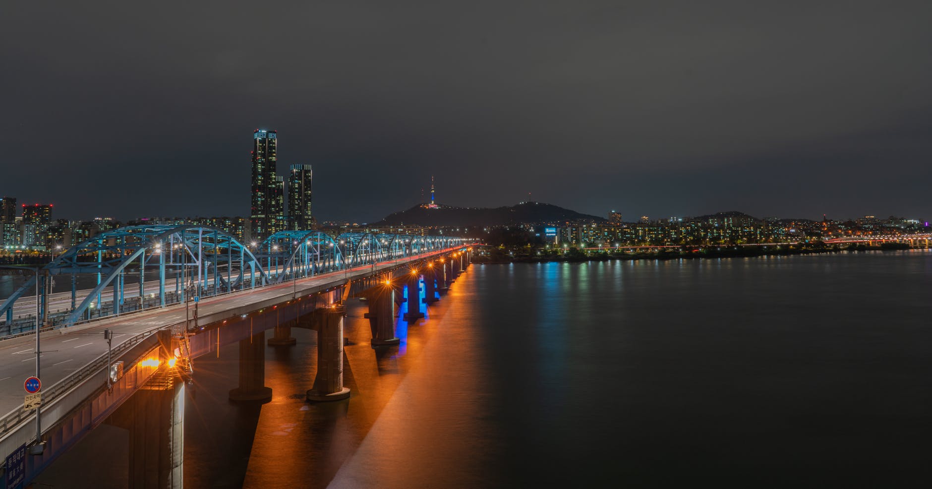 Captivating night view of Seoul's illuminated skyline and Han River Bridge.