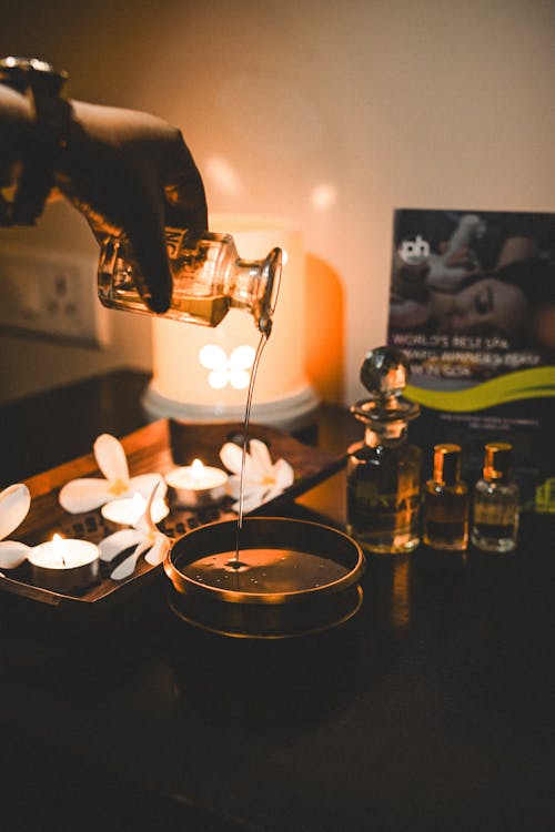 A person pouring some oil into a candle