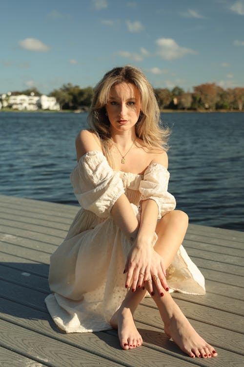 A beautiful blonde woman sitting on a dock