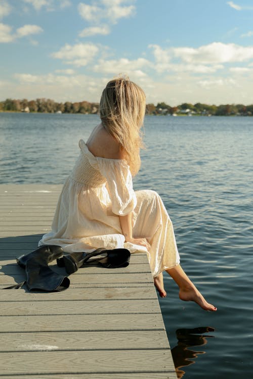 A woman sitting on a dock by the water