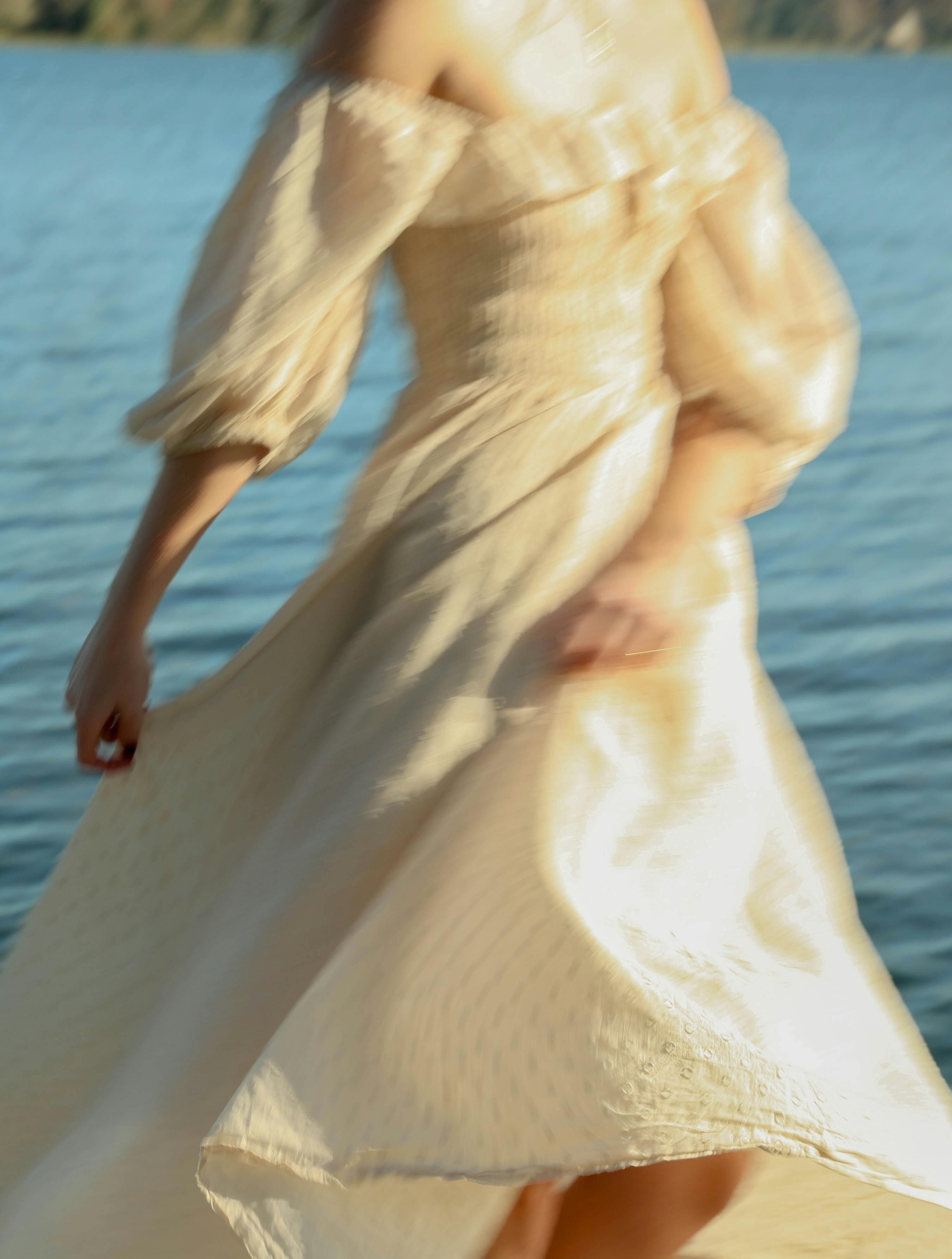 Caucasian woman in a flowing white dress spinning by a lake in Orlando, Florida.