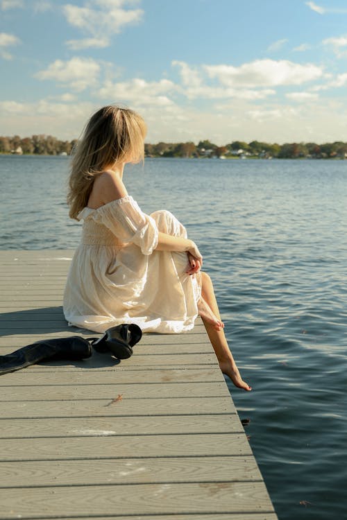 A woman sitting on a dock looking at the water