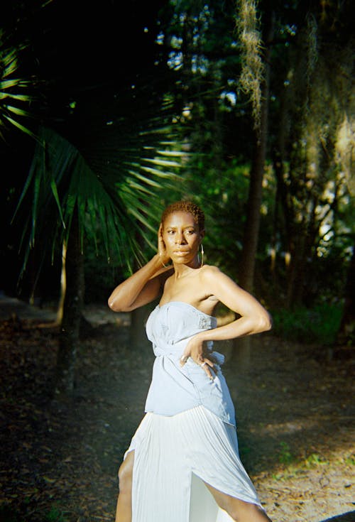 A woman in a white dress posing in the woods