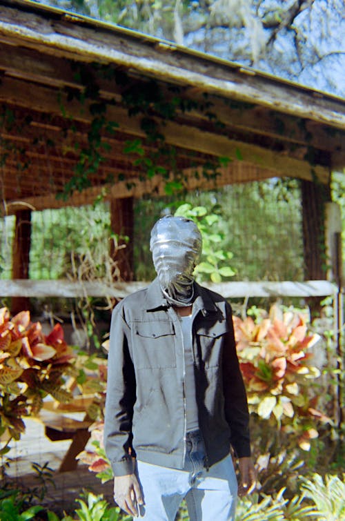 A man in a mask standing in front of a house
