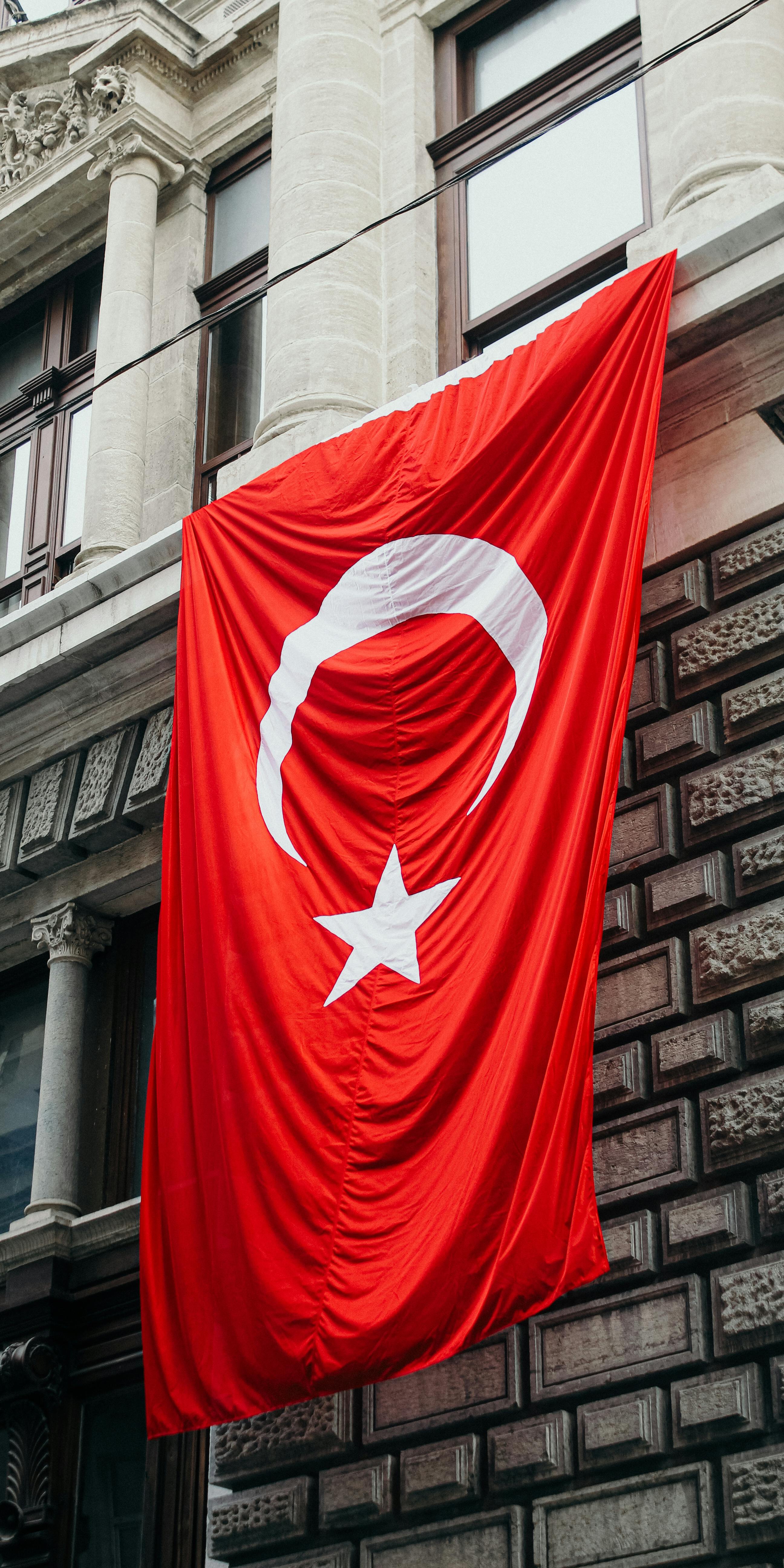 Vertical shot of the Turkish flag on a historic Istanbul building, symbolizing national pride.