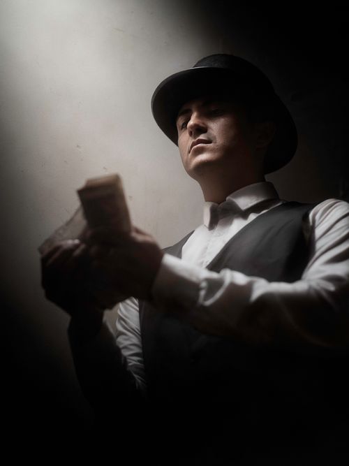 Free Moody portrait of a man in a hat counting money, dimly lit. Stock Photo