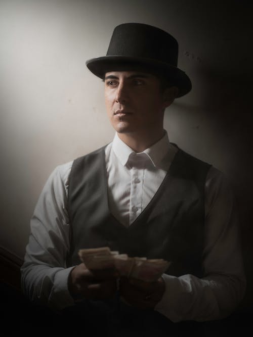 A man in a hat and vest holding money