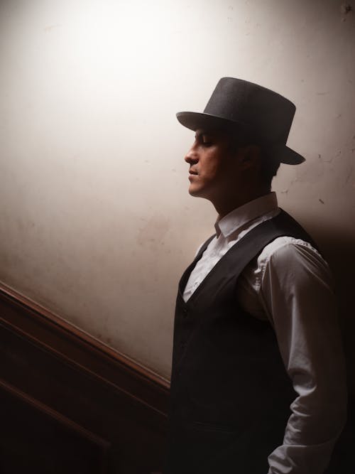 A man in a hat and vest stands in a stairwell