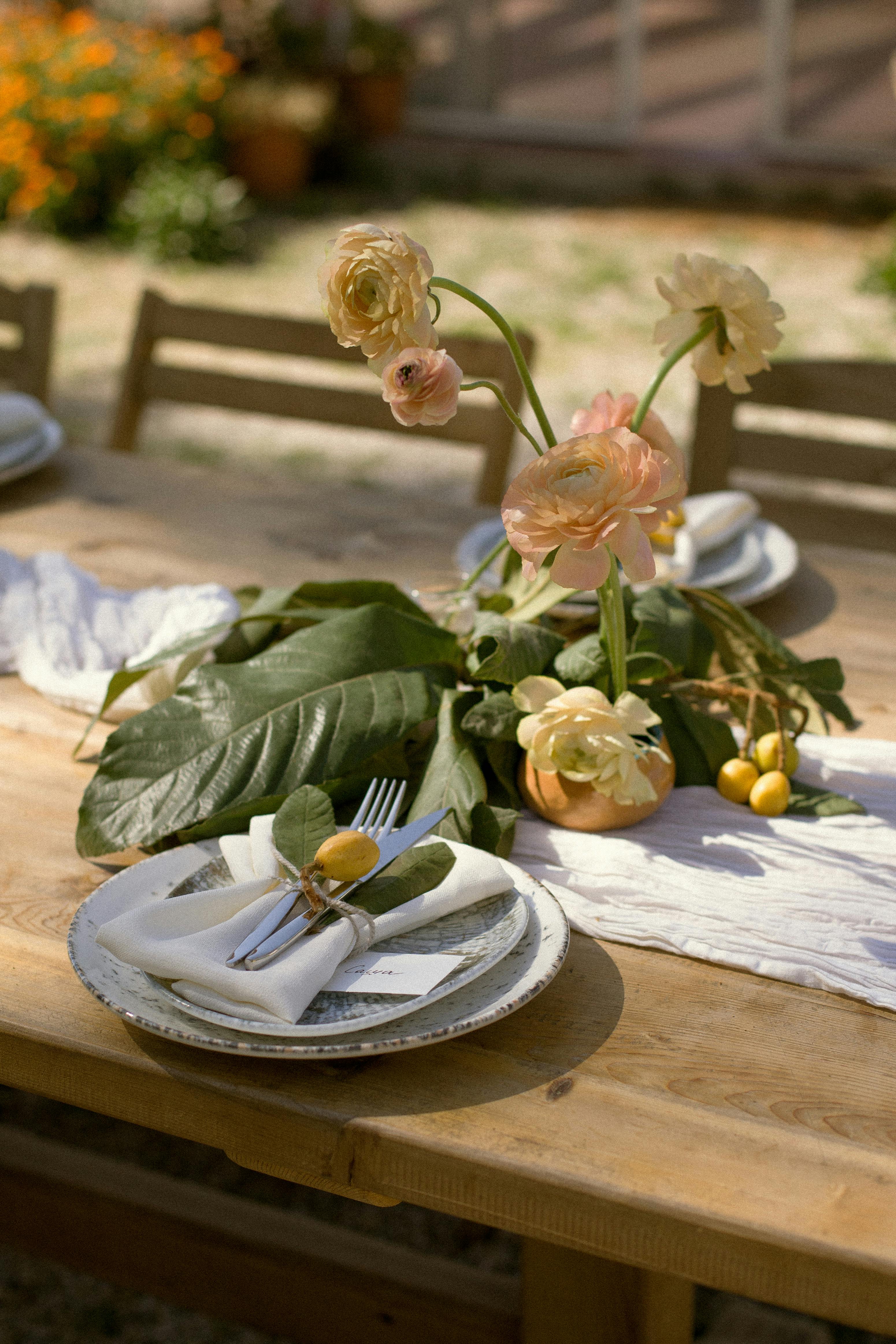 Elegant outdoors table with flowers and tableware for a summer gathering.