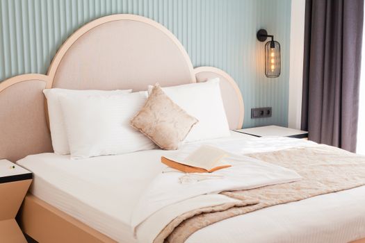A luxurious hotel bedroom featuring elegant bedding and an open book, exuding comfort and style.