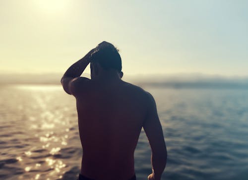 Topless Man Standing and Touching His Head