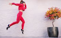 一位充满活力的女人穿着红色运动服在户外跳跃，展现了健身的活力与时尚