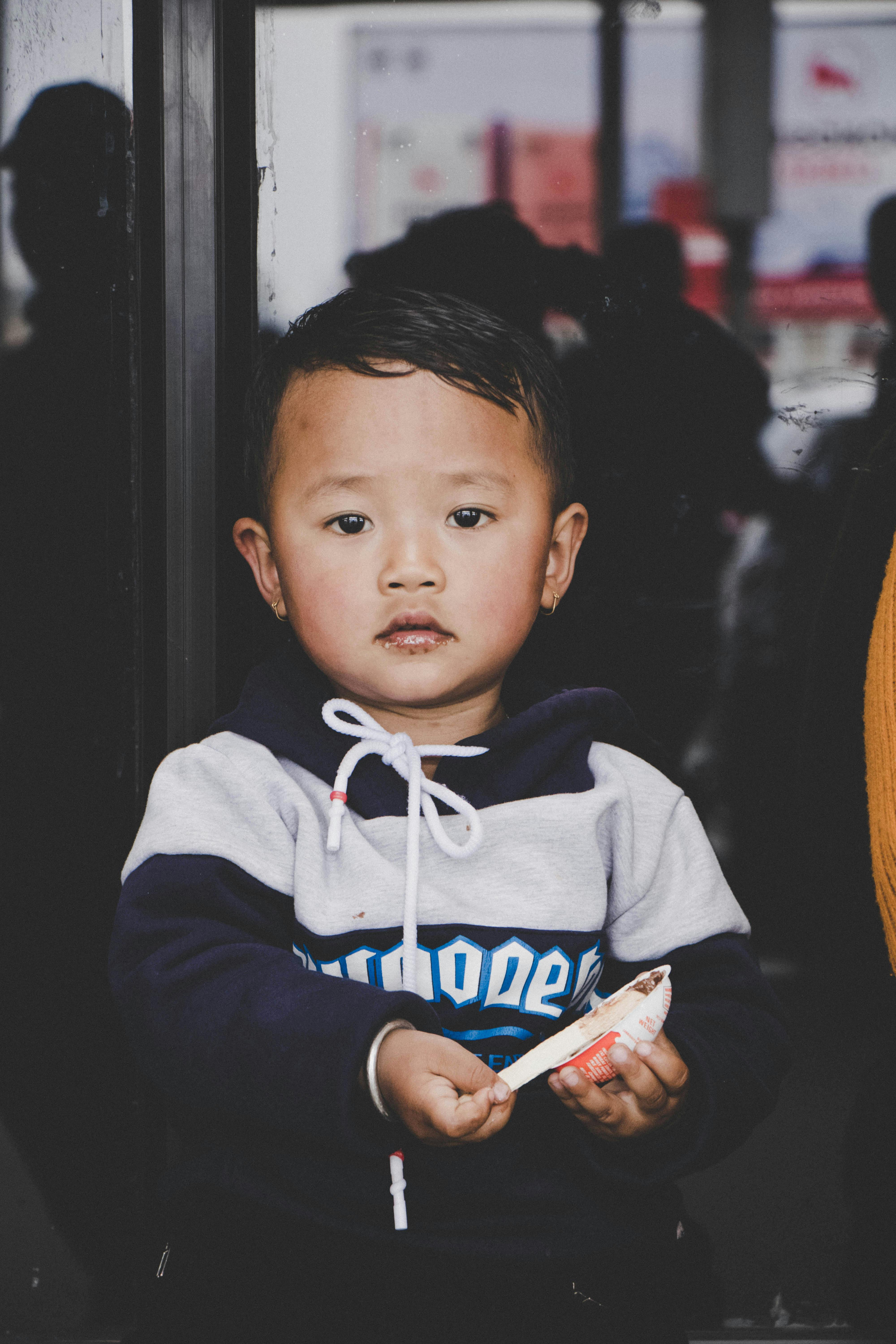 A cute toddler with an innocent expression holding a toy inside a cozy setting.
