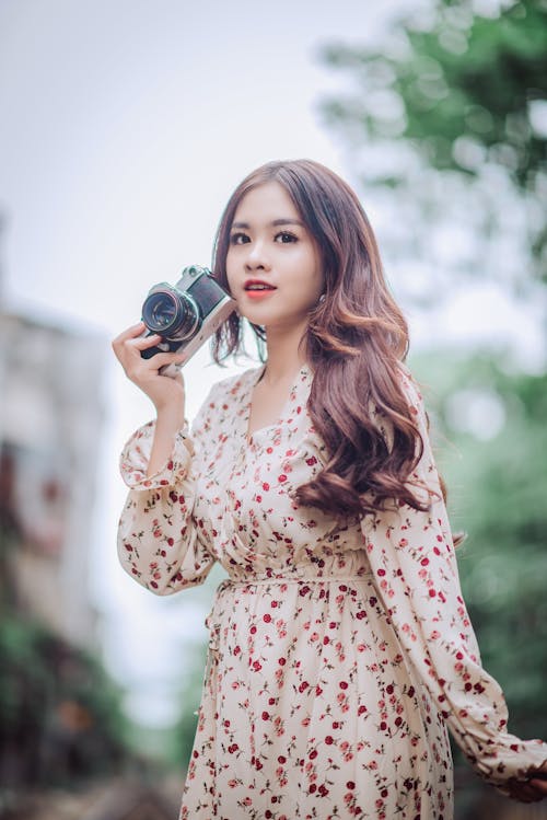 Woman in Floral Dress Holding Ccamera