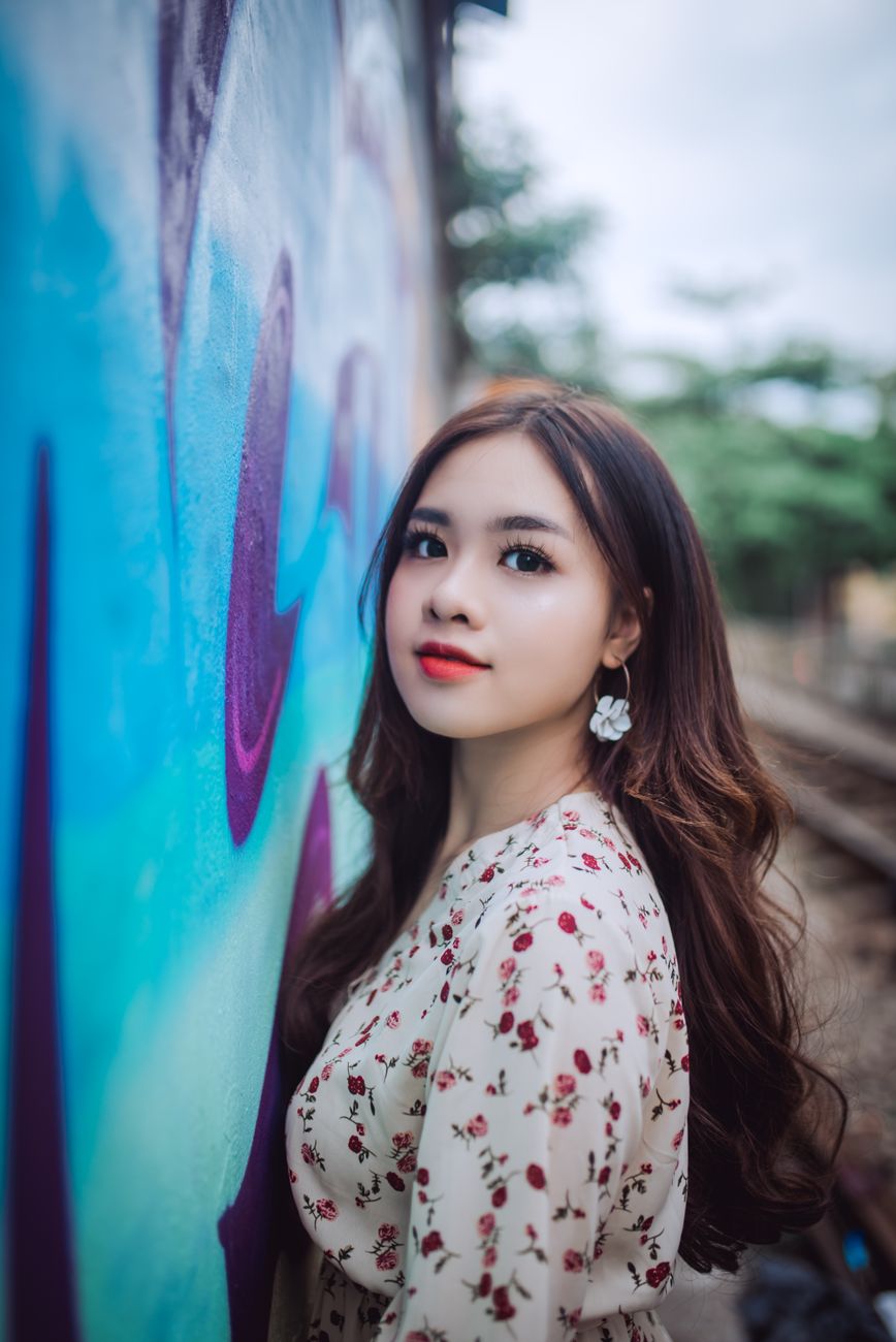 Elegant woman posing by a vibrant graffiti wall, exuding charm and sophistication.