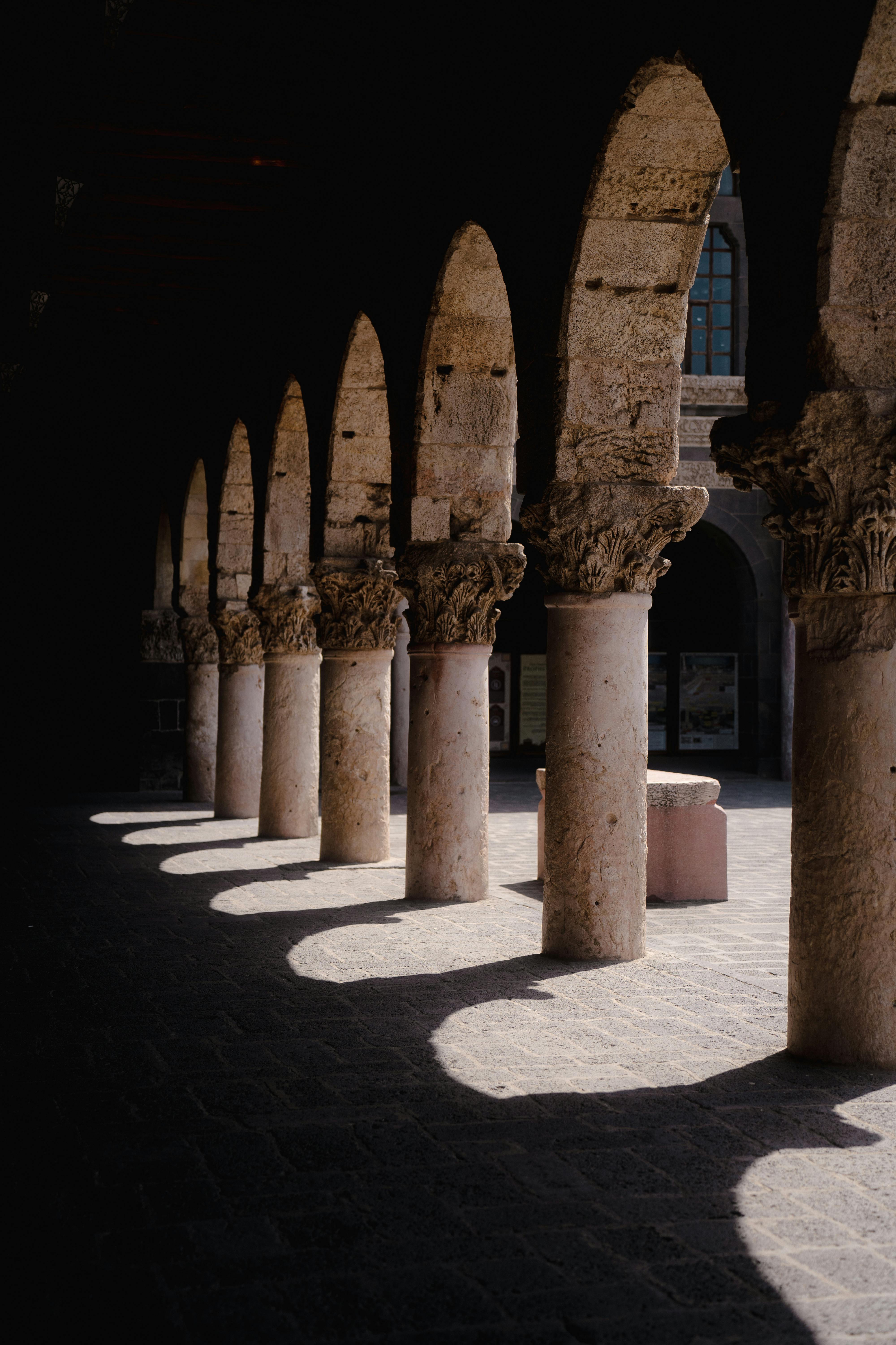 Shadowed colonnade with historic arches in Diyarbakir, showcasing Ottoman architectural beauty.