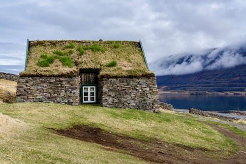 Free Historic Stone House with a Roof Overgrown with Grass in an Icelandic Fjord Stock Photo