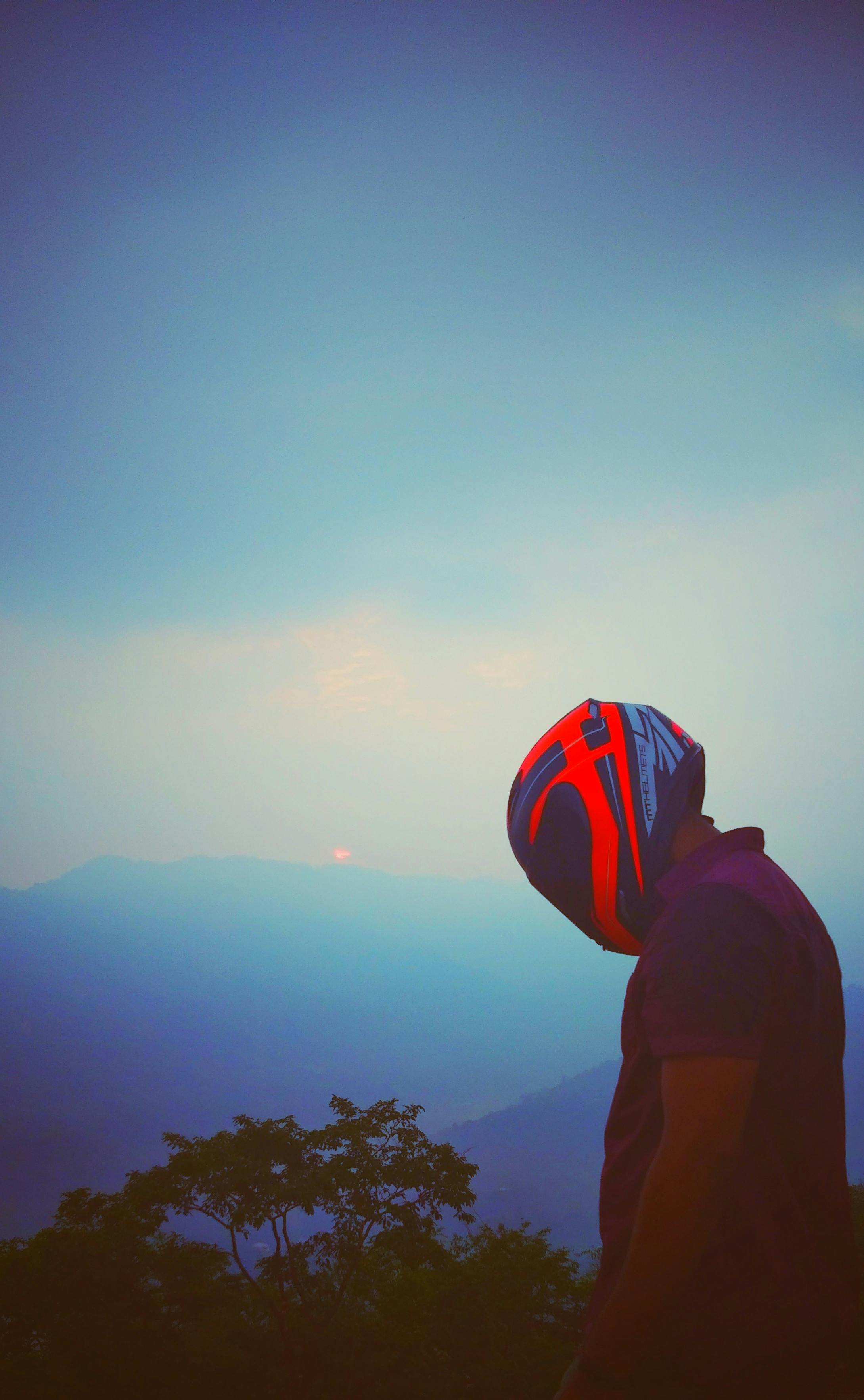 一个人戴着头盔，在壮丽的山间日落映衬下，形成戏剧性的剪影