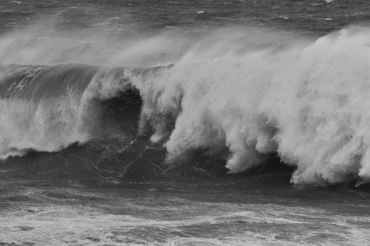 black and white photo of powerful ocean waves crashing dramatically at
