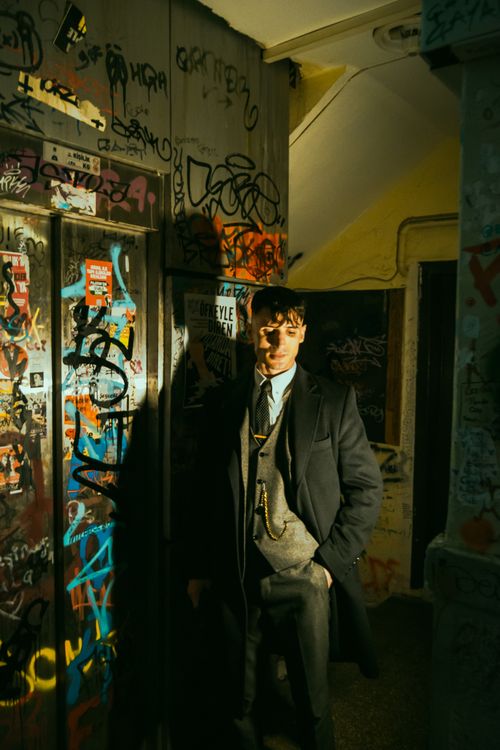 Free Man in vintage suit stands amidst vibrant urban graffiti, creating a dramatic contrast. Stock Photo