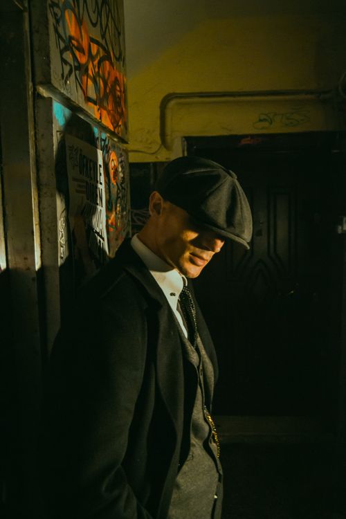 Free An elegant man in retro fashion wearing a hat and tie poses in an urban setting with graffiti. Stock Photo
