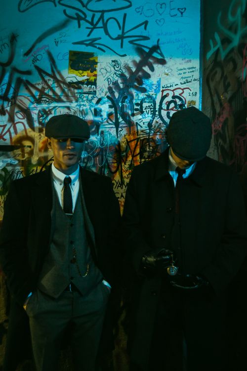 Free Two men in vintage suits and hats stand against a graffiti wall, capturing a cool, urban vibe. Stock Photo