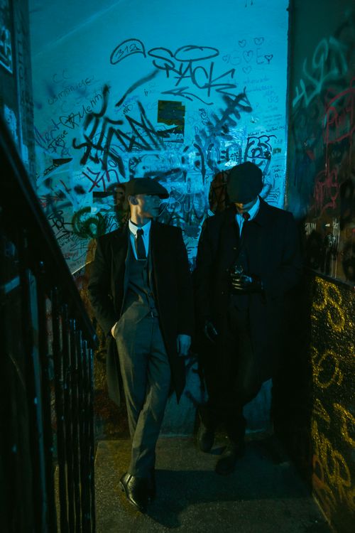 Free Two stylish men in retro suits and hats standing in a graffiti-covered alleyway at night. Stock Photo