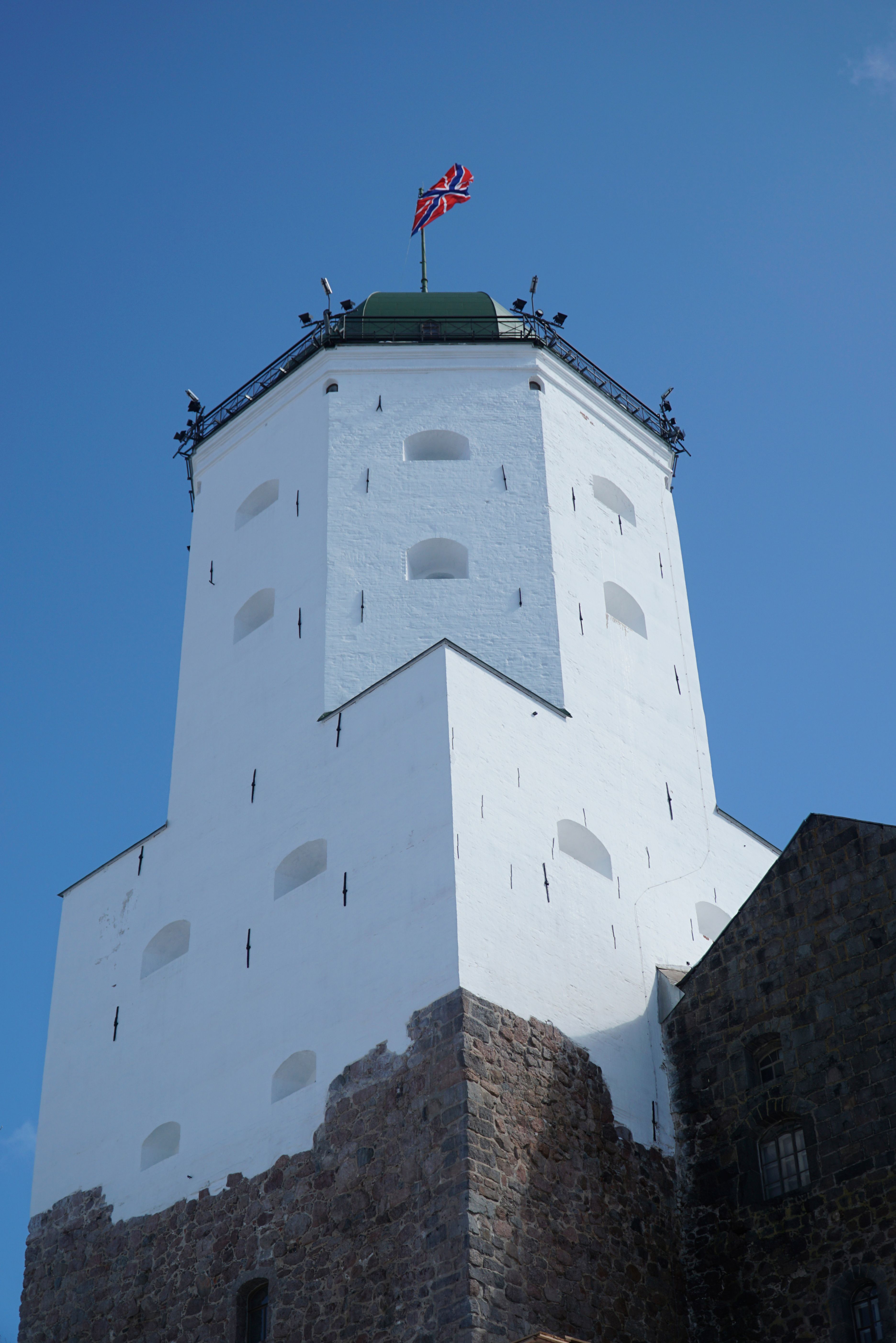 Tower of Vyborg Castle with a prominent flag under a clear blue sky.