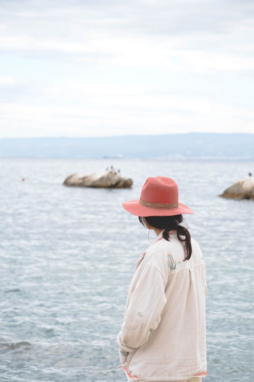 A woman in a hat looking out to the ocean