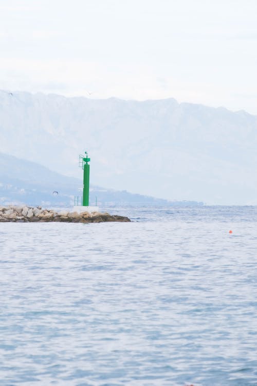 A lighthouse in the ocean with mountains in the background